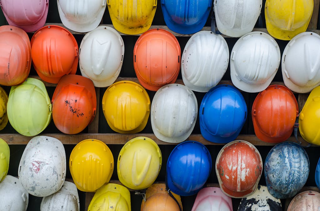 Vibrant collection of industrial safety helmets neatly arranged on a wall.