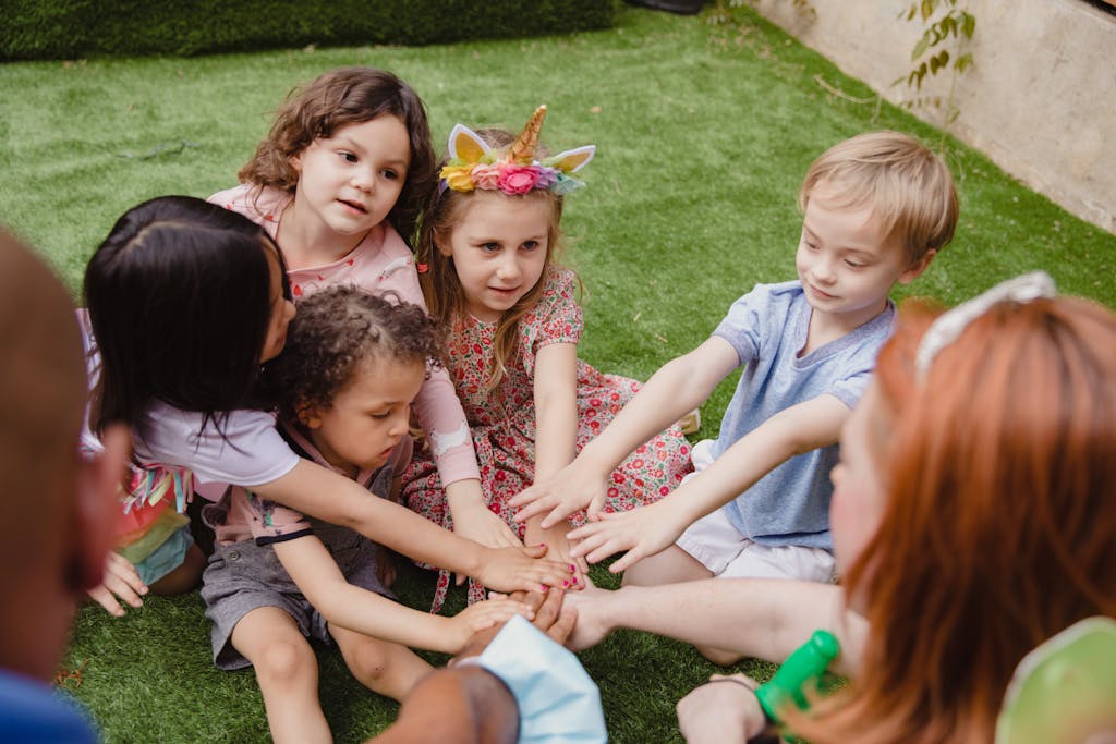 Group of children enjoying a birthday party outdoors, hands in a circle celebrating friendship.